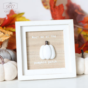 The Autumn Pumpkin 3D Framed Plaque With Quotes features a white pumpkin in the center, set against a light wood background and displaying the text "Meet me at the pumpkin patch." Surrounded by white pumpkins and autumn leaves, this delightful piece enhances your space with charming fall-themed decor.