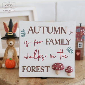 An Autumn Easel Sign with 3D Resin Toadstools, featuring the text "Autumn is for family walks in the forest," is displayed. The sign includes Fall Decorations such as decorative leaves and 3D Resin Toadstools. In the background, there's a stuffed rabbit wearing a witch hat and a small toy house.