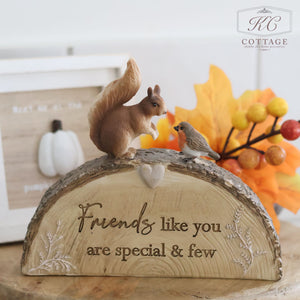 The Autumn Woodland Animal Ornament With Bark Effect Base and Quote showcases a charming scene of a squirrel and a small bird resting on a log, accompanied by an inspiring message: "Friends like you are special & few." The log has a realistic bark texture, set against a backdrop featuring autumn leaves, berries, and a white pumpkin decoration. The "KC Cottage" logo is placed in the top right corner.