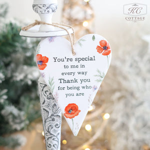 The Ceramic Poppy Hanging Heart with Friendship Quote showcases red poppies and green leaves against a blurred backdrop. The text says, "You're special to me in every way. Thank you for being who you are." It's an ideal gift for a friend, featuring a heartwarming friendship message.