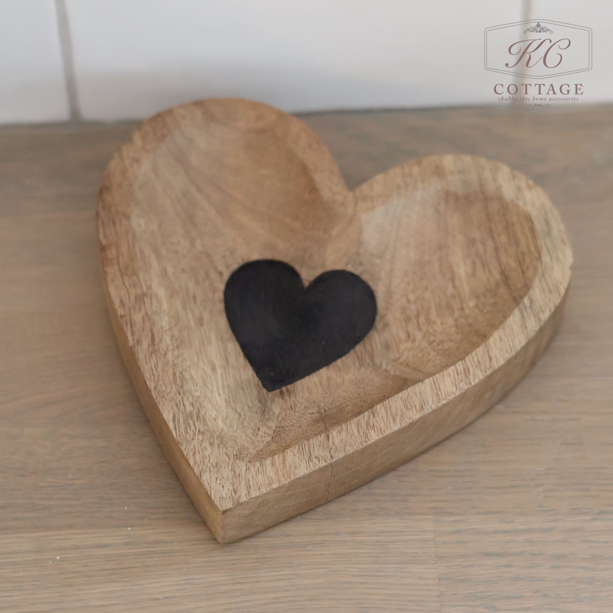 A Rustic Wooden Heart Tray with an etched heart in the center sits elegantly on a wooden surface, with the "KC Cottage" logo displayed in the upper corner, adding a farmhouse-style touch to this charming piece.